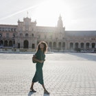 Smiling young woman looking away while walking at Plaza De Espana, Seville, Spain